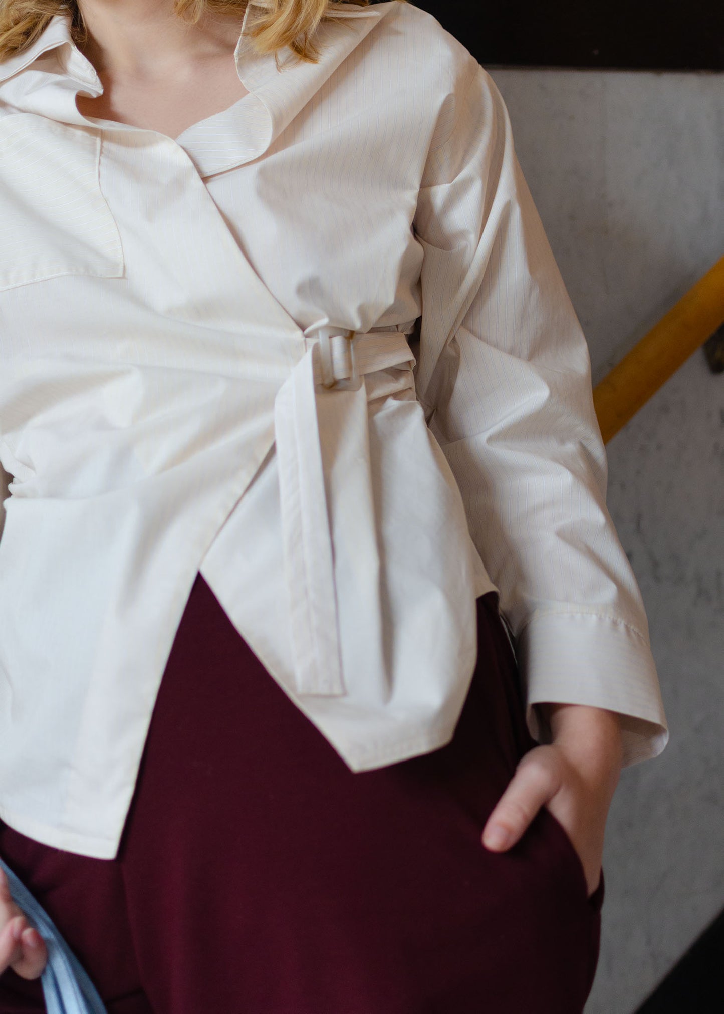 Detail view, light yellow long sleeve cotton poplin shirt with adjustable closure at front. Asymmetrical front.