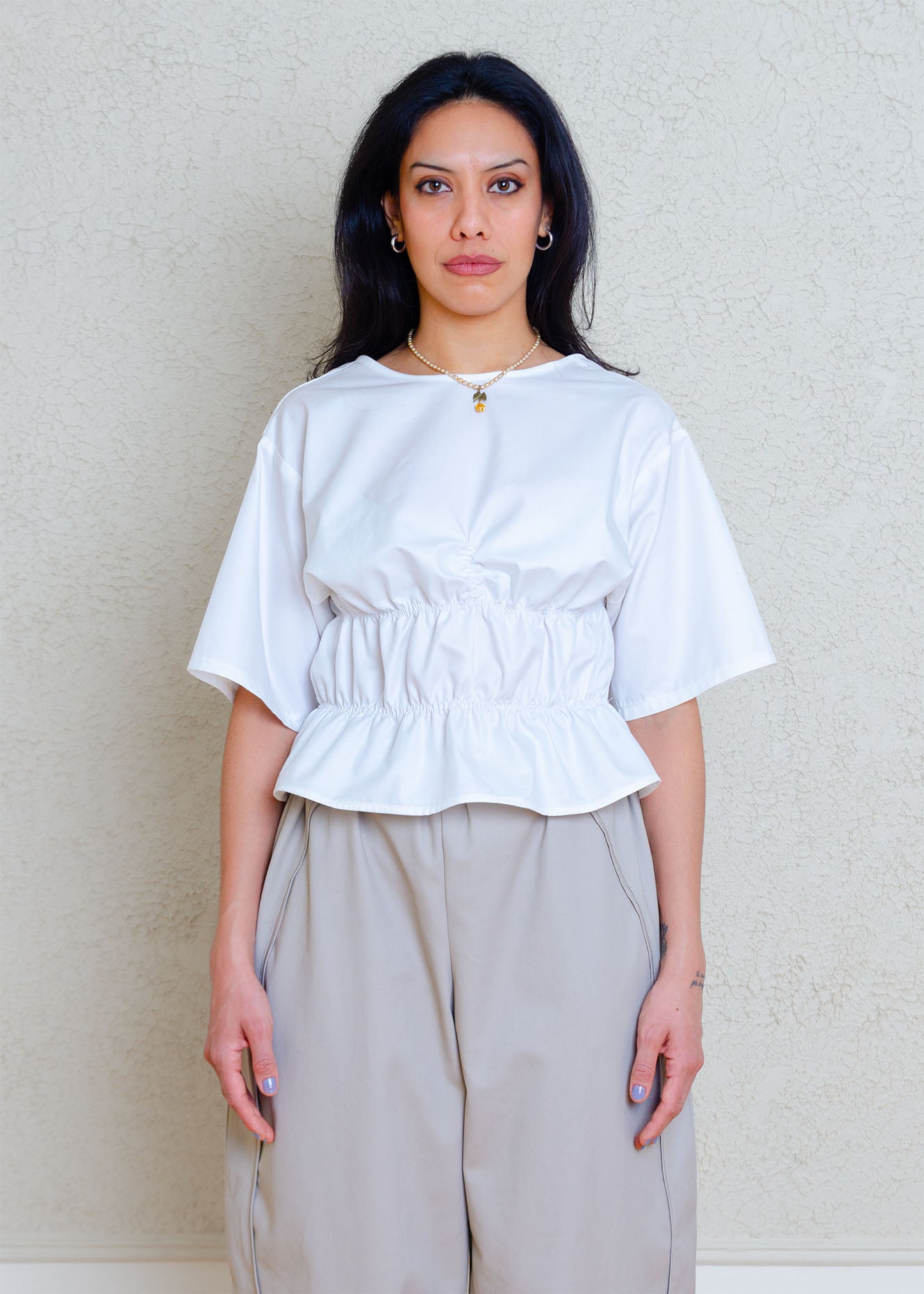 Rouched short sleeve top with dropped shoulders and low back. Elasticized waist detailing allows for a greater size variation. Crisp cotton poplin fabric
