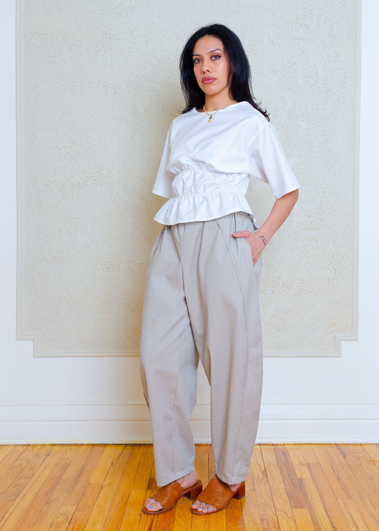 Three quarter view Rouched short sleeve top with dropped shoulders and low back. Elasticized waist detailing allows for a greater size variation. Crisp cotton poplin fabric