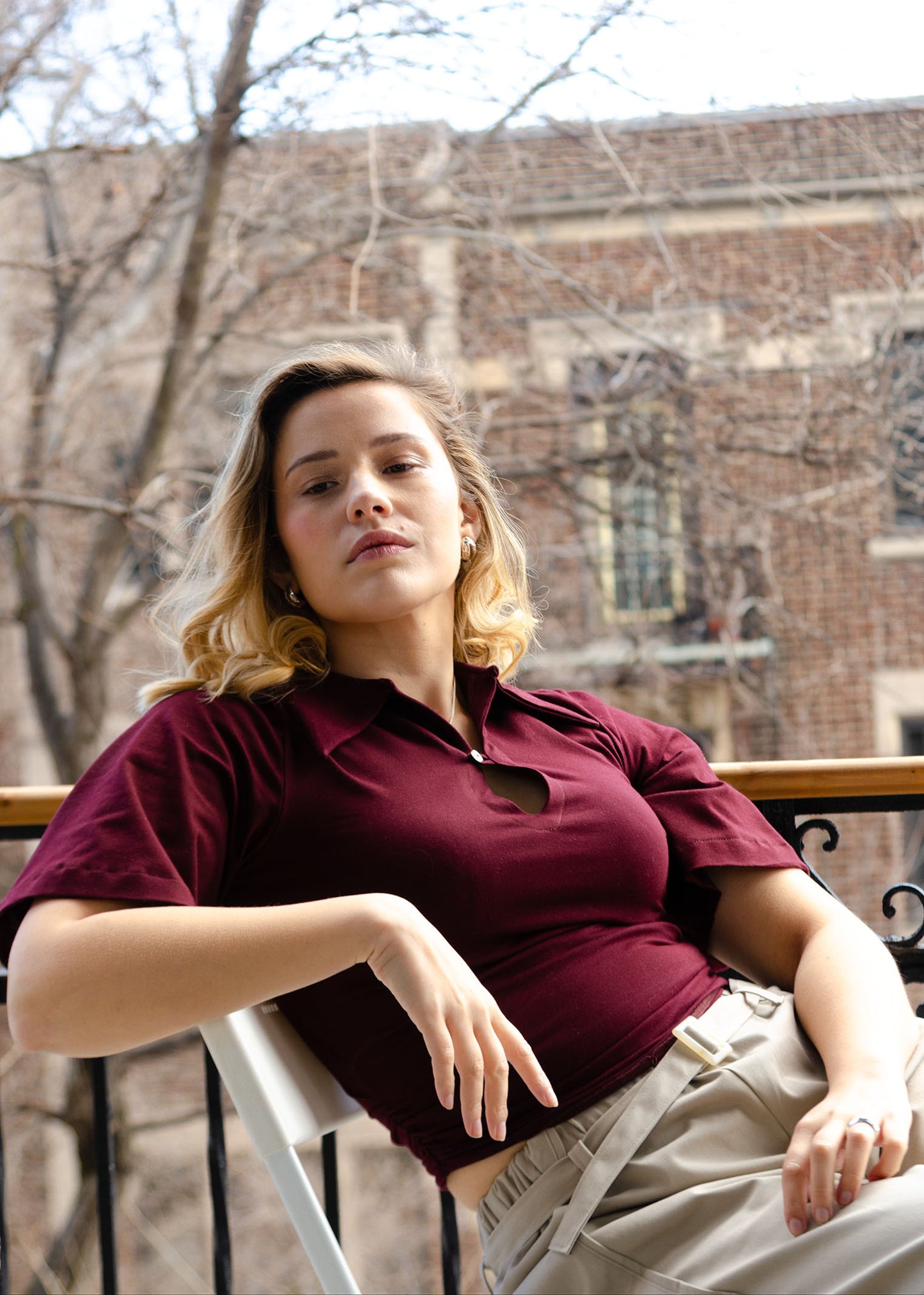Waist length, fitted stretch knit polo top with button & loop detail, oversized collar, rouching at the side seams and flared sleeves just ending above the elbow.