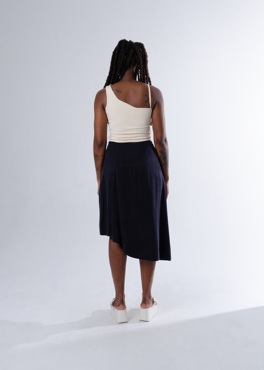 Cream cropped cotton tank top back view. Black A-line midi skirt with wavy asymmetrical hem