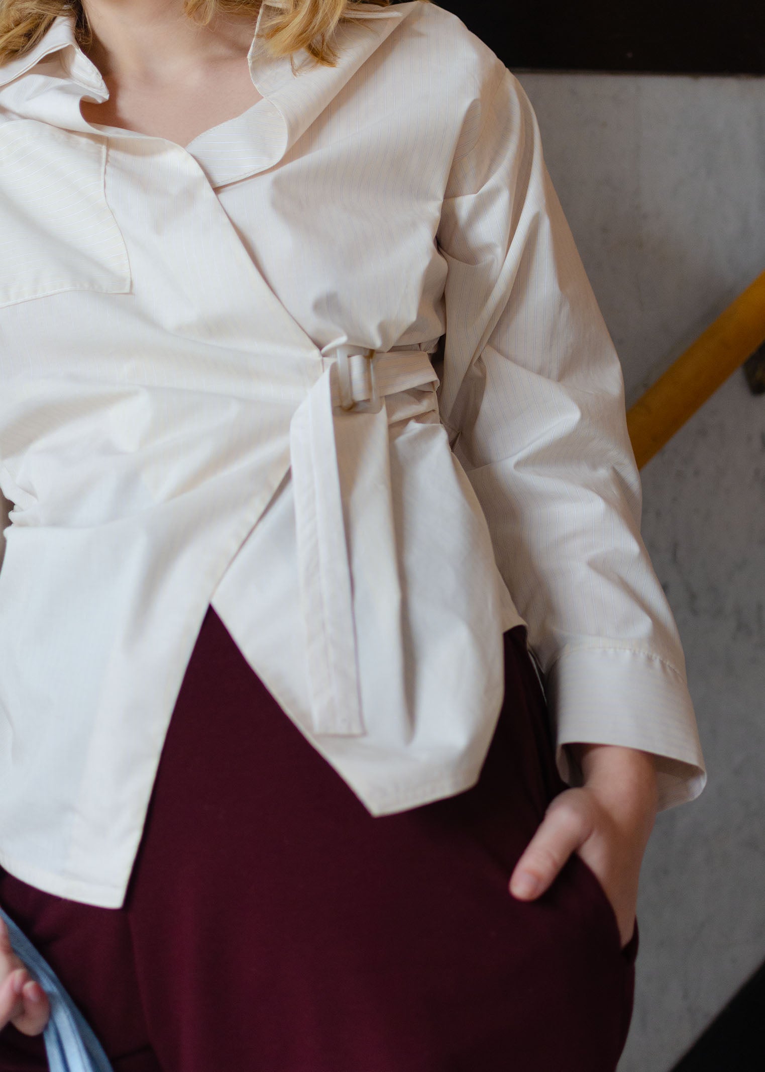 Detail view, light yellow long sleeve  cotton poplin shirt with adjustable closure at front. Asymmetrical front.