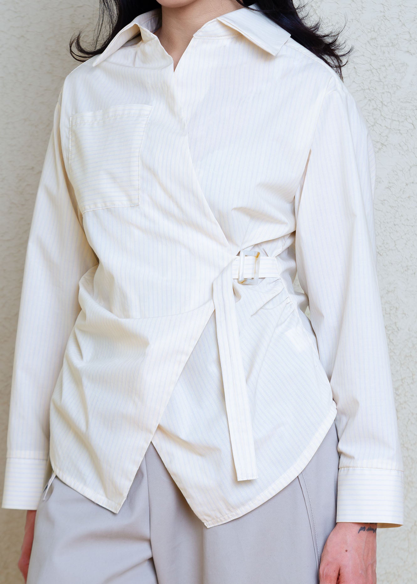 Cotton poplin shirt with asymmetrical front, adjustable waist closure with matte tortoiseshell print slider, gathering at waist side seams, shirt collar & patch pocket.Featuring an exaggerated baseball hem & back darts for a flattering, slightly fitted look.

Lightweight light yellow cotton poplin fabric features a subtle menswear-influenced stripe. 
