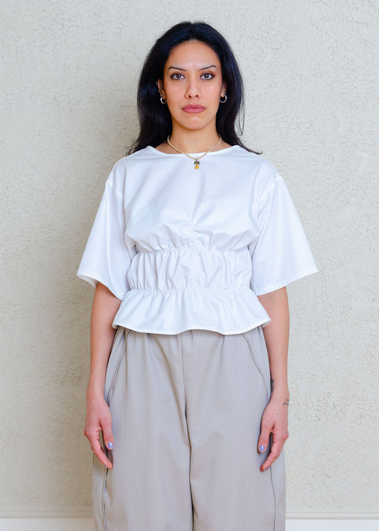 Rouched short sleeve top with dropped shoulders and low back. Elasticized waist detailing allows for a greater size variation. Crisp cotton poplin fabric