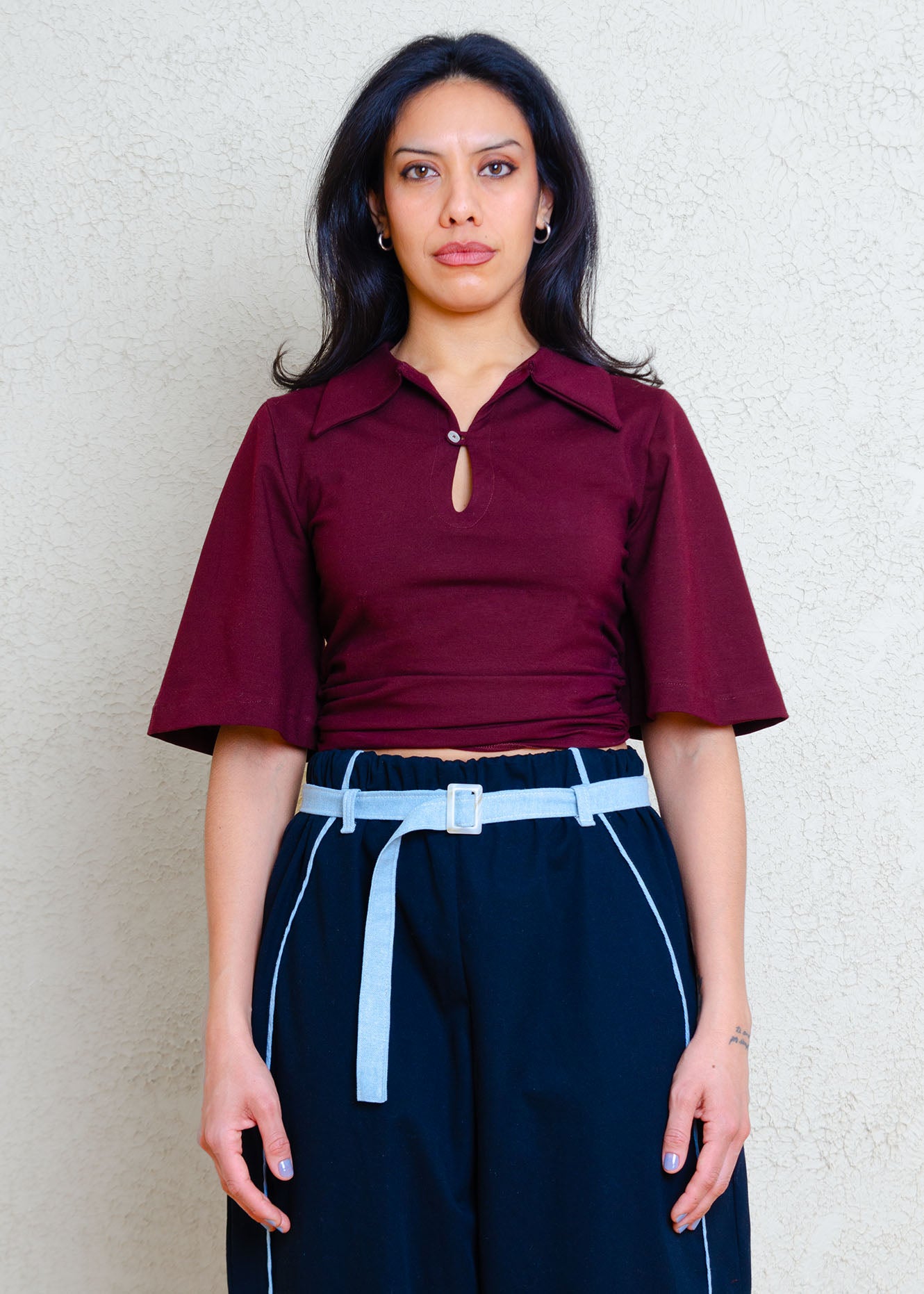 Fitted stretch knit polo top with button &  loop detail, oversized collar, rouching at the side seams and flared sleeves just ending above the elbow.

This is our version of the classic polo- slightly exaggerated proportions & subtle detailing instantly updates this shirt from staple to statement.

This top ends sits just below the natural waist and pairs perfectly with our "Cat" knit shorts.
