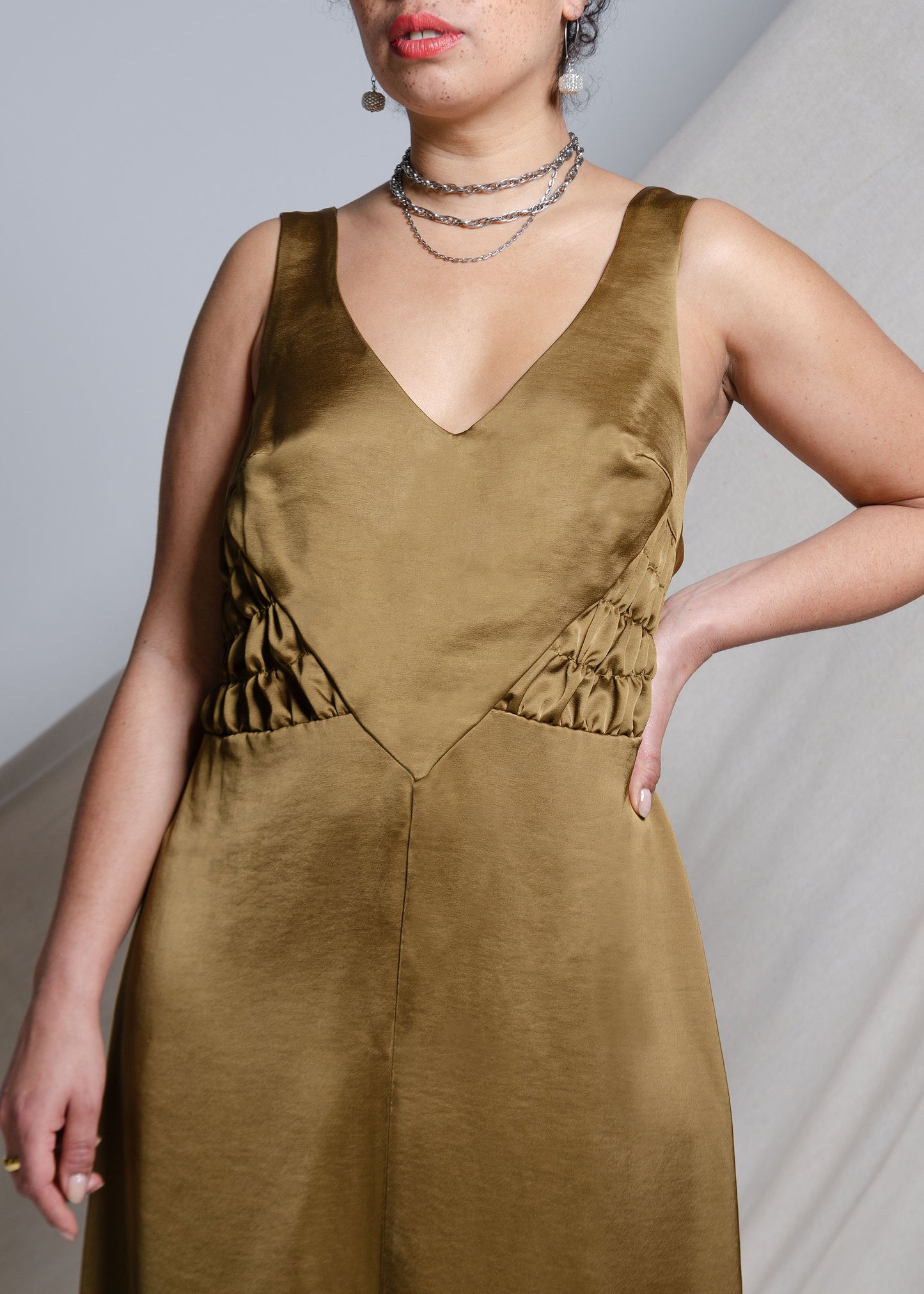 Form skimming Midi length A-line dress with gathered side panels and very low back. Khaki  green satin fabric