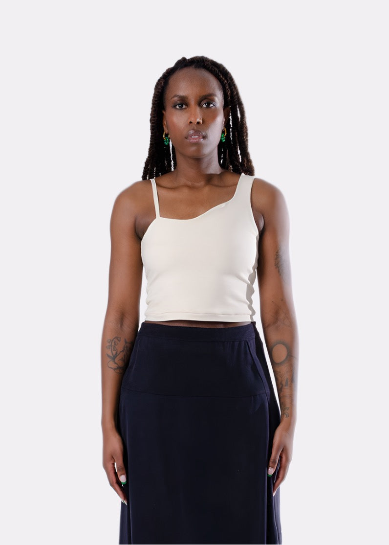 3/4 picture of woman wearing cream cotton cropped tank top with wavy detail and asymmetrical straps